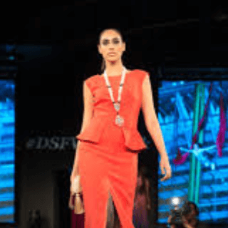 Model walking on a fashion runway wearing a red dress, representing audiences interested in fashion, luxury brands, and style trends.