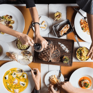 Group of people enjoying gourmet dishes at a restaurant, representing foodie audiences who explore dining experiences, fine cuisine, and gastronomy trends.
