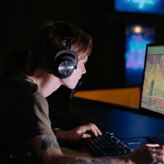 Young gamer wearing headphones and playing on a computer, representing audiences passionate about gaming, eSports, and digital entertainment.