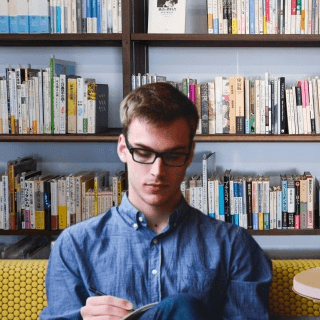 Young professional reading and working in a modern office, representing audiences of entrepreneurs, startup founders, and small business owners.