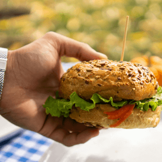 Hand holding a veggie burger, representing audiences interested in healthy food, plant-based products, and wellness lifestyles.